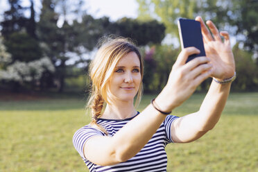 Porträt einer entspannten blonden Frau, die ein Selfie mit ihrem Smartphone macht - GIOF001000