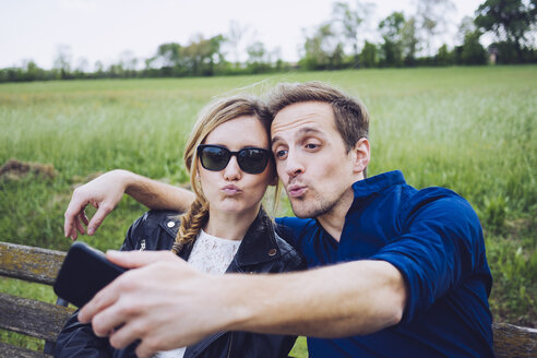Porträt eines Paares mit schmollenden Mündern, das ein Selfie mit einem Smartphone macht - GIOF001004