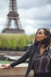 France, Paris, Young woman standing on bridge with theEiffel Tower in background - ZEDF000114