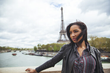 France, Paris, Young woman standing on bridge with theEiffel Tower in background - ZEDF000115