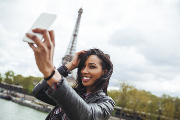 Frankreich, Paris, Junge Frau nimmt Smartphone-Selfie vor dem Eiffelturm - ZEDF000116