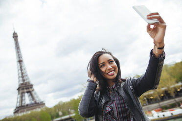Frankreich, Paris, Junge Frau nimmt Smartphone-Selfie vor dem Eiffelturm - ZEDF000117