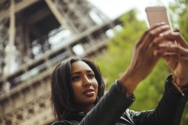 Frankreich, Paris, Junge Frau nimmt Smartphone-Selfie vor dem Eiffelturm - ZEDF000120