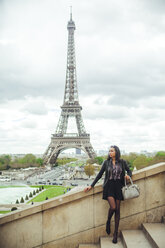 France, Paris, Young woman standing on bridge with theEiffel Tower in background - ZEDF000121