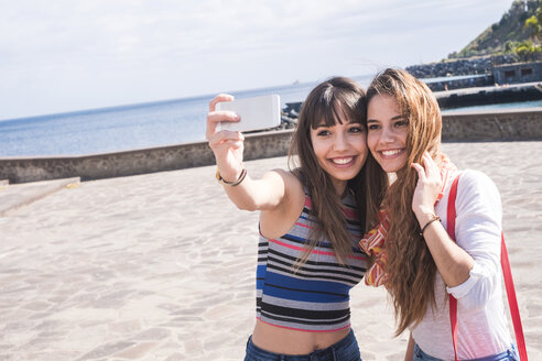 Zwei lächelnde Freunde an der Küste machen ein Selfie - SIPF000445