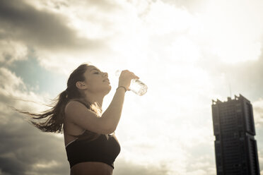 Sportliches junges Mädchen trinkt Wasser aus einer Flasche - SIPF000451