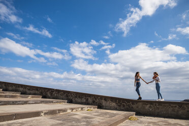 Two friends walking hand in hand on a wall - SIPF000458