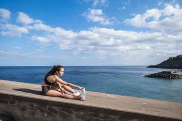 Athletic teenage girl stretching at the ocean - SIPF000465