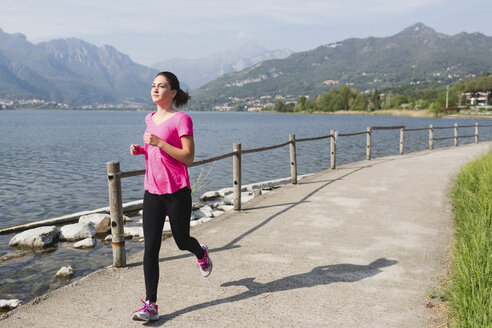 Italien, Lecco, junge Frau läuft am See entlang - MRAF000016