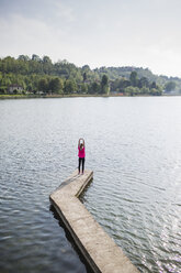 Italien, Lecco, junge Frau streckt sich am See - MRAF000021