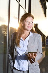 Portrait of businesswoman with digital tablet at evening twilight - MAEF011721