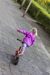 Rückansicht eines kleinen Mädchens, das auf seinem Roller balanciert - JFEF000780