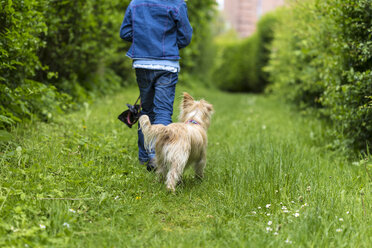 Rückenansicht eines kleinen Mädchens, das mit ihrem Hund in der Natur spazieren geht - JFEF000798