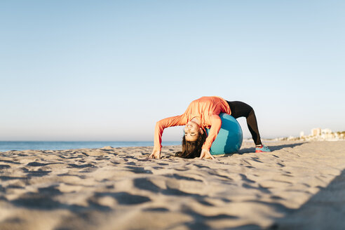 Frau beim Sport mit Gymnastikball früh am Morgen am Strand - JRFF000666