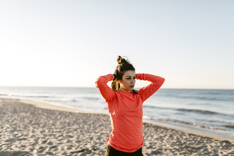 Woman running on the beach early in the morning, hands in hair stock photo