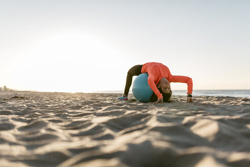 Frau beim Sport mit Gymnastikball früh am Morgen am Strand - JRFF000668