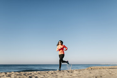 Frau joggt frühmorgens am Strand - JRFF000674