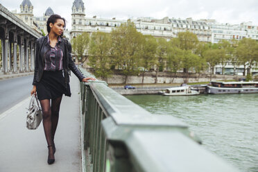France, Paris, young woman walking on bridge - ZEDF000128