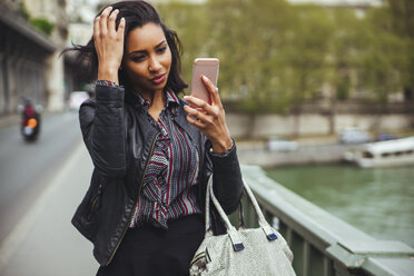 Frankreich, Paris, junge Frau schaut auf ihr Smartphone - ZEDF000130