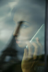 Frankreich, Paris, junge Frau schaut beim Telefonieren durch das Autofenster - ZEDF000135