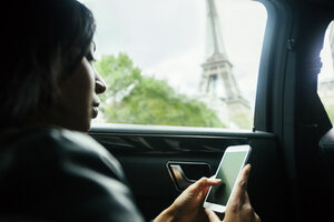 Frankreich, Paris, junge Frau sitzt in einem Auto und schaut auf ihr Smartphone - ZEDF000136