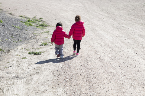 Back view of two little sisters walking hand in hand stock photo