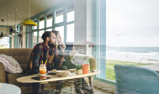 Spanien, Asturien, Paar genießt beim Brunch die Meereslandschaft durch das Fenster des Cafés - DAPF000093