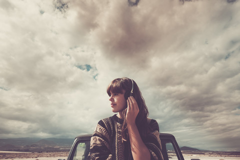 Junge Frau, die unterwegs ist und mit Kopfhörern Musik hört, lizenzfreies Stockfoto