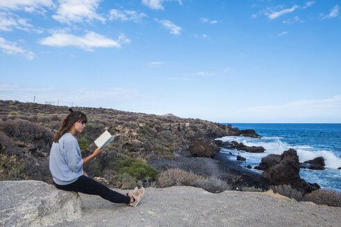 Junge Frau beim Lesen eines Buches am Meer - SIPF000475