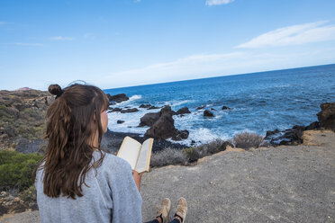 Young woman reading book at the sea - SIPF000476