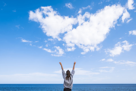 Junge Frau streckt ihre Arme in den Himmel, lizenzfreies Stockfoto