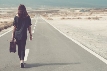 Young woman with suitcase walking on a road - SIPF000484