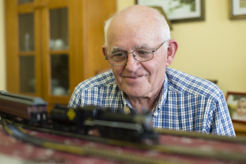 Porträt eines lächelnden älteren Mannes mit seiner Modelleisenbahn, lizenzfreies Stockfoto