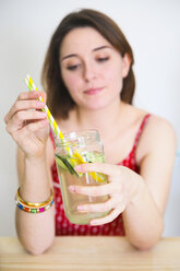 Frau hält ein Glas Entgiftungswasser mit Zitrone und Gurke in der Hand - RTBF000210