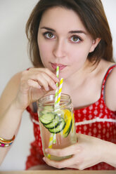 Porträt einer Frau, die mit Zitrone und Gurke angereichertes Entgiftungswasser trinkt - RTBF000211