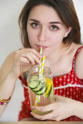 Portrait of woman drinking detox water infused with lemon and cucumber - RTBF000211