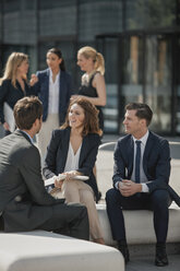 Business colleagues talking outside office building - CHAF001727