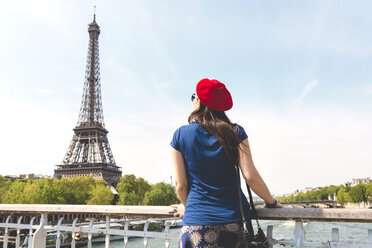 Frankreich, Paris, Rückenansicht einer Frau mit roter Baskenmütze mit Blick auf den Eiffelturm - GEMF000897