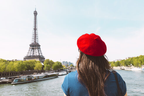 Frankreich, Paris, Rückenansicht einer Frau mit roter Baskenmütze mit Blick auf den Eiffelturm - GEMF000898