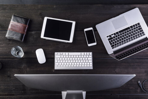 Desk with computer and various digital gadgets, overhead view - HAPF000351