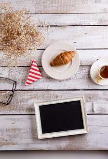 Tisch mit Croissant, Tee und schwarzem Brett mit Kopierfläche - HAPF000353