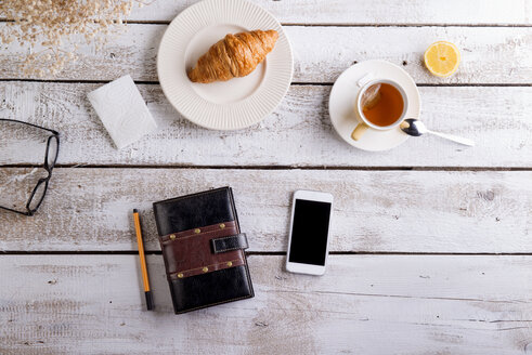 Tisch mit Croissant, Tee, Smartphone und persönlichem Organizer - HAPF000354