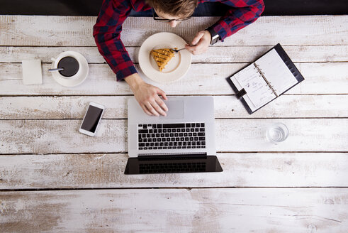 Mann arbeitet am Laptop bei Kaffee und Kuchen - HAPF000363