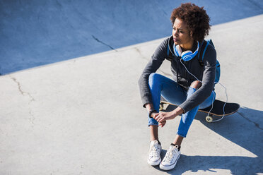 Young woman sitting on skateboard - UUF007247