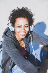 Porträt einer lächelnden jungen Frau mit Kopfhörern im Freien - UUF007252