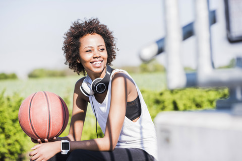 Lächelnde junge Frau hält Basketball, lizenzfreies Stockfoto
