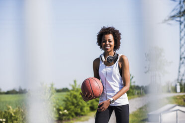 Lächelnde junge Frau hält Basketball - UUF007285