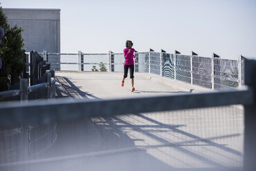 Young woman running on parking deck - UUF007290