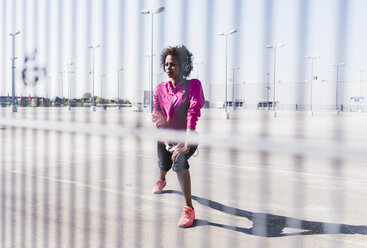 Young woman stretching on parking lot - UUF007293