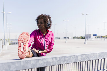 Young woman stretching on parking lot - UUF007294